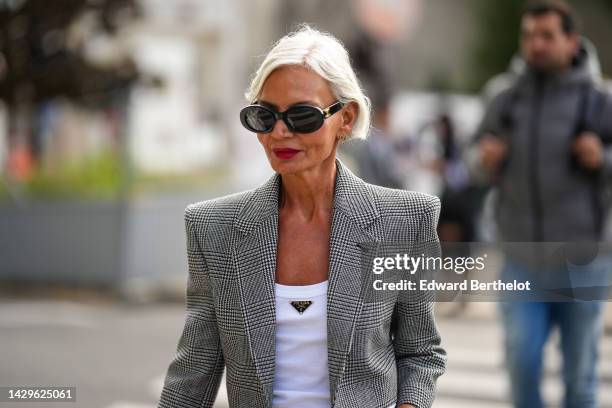 Grece Ganhem wears black sunglasses from Celine, gold and diamonds earrings from Messika, a black and white houndstooth print pattern shoulder-pads /...