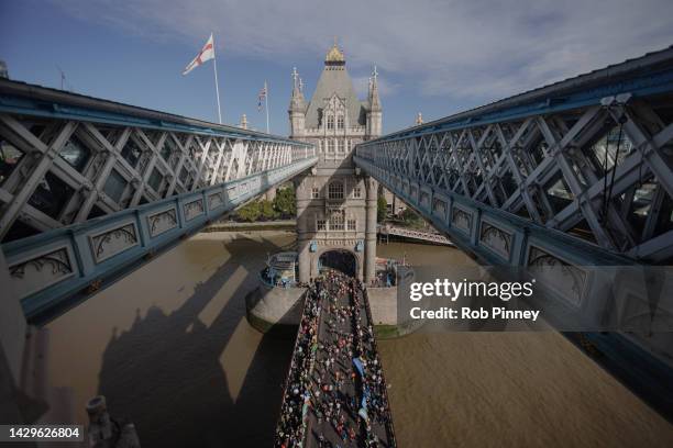 Runners cross Tower Bridge during the London Marathon on October 02, 2022 in London, England. The view is as seen from the high-level glass floor of...