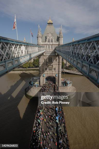 Runners cross Tower Bridge during the London Marathon on October 02, 2022 in London, England. The view is as seen from the high-level glass floor of...
