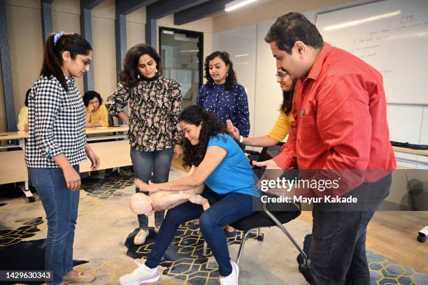 woman trainee practicing heimlich manoeuver on a child mannequin during choking in cpr first aid training - choking stock pictures, royalty-free photos & images