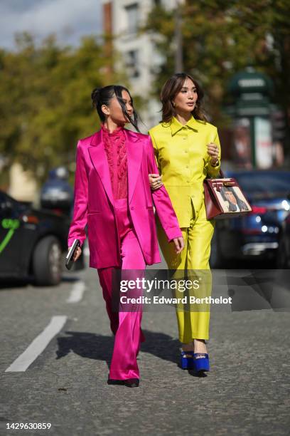 Nikki Huang wears diamond earrings, a neon pink ruffled lace print pattern high neck shirt, a neon pink shiny silk / satin long blazer jacket,...