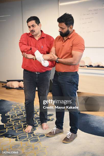 male instructor showing basic first aid bandaging during first aid training class - first aid stock pictures, royalty-free photos & images