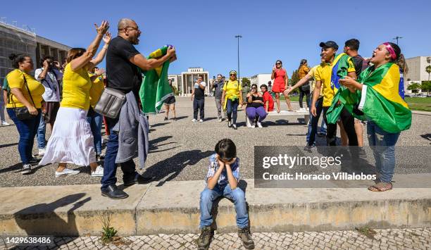 Little boy sits on the curb and covers his ears while Brazilian supporters of opposition candidate Lula da Silva and Bolsonaro's supporters trade...