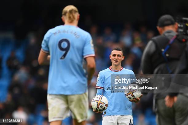Phil Foden of Manchester City hands a match ball to team mate Erling Haaland after both scoring a hat trick during the Premier League match between...