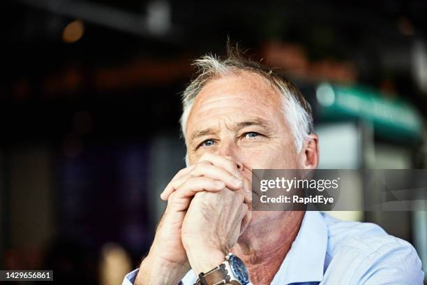 handsome middle-aged man looking serious and thoughtful, resting his chin on his hands - mid adult men stock pictures, royalty-free photos & images