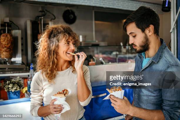 porträt eines mannes und einer frau, die gyros essen - shawarma stock-fotos und bilder