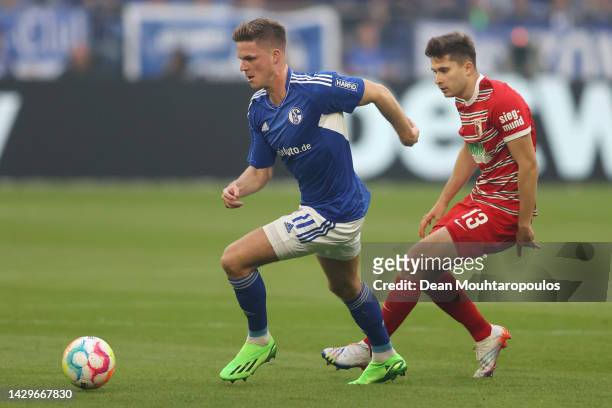 Marius Bulter of FC Schalke 04 battles for possession with Elvis Rexhbecaj of Augsburg during the Bundesliga match between FC Schalke 04 and FC...