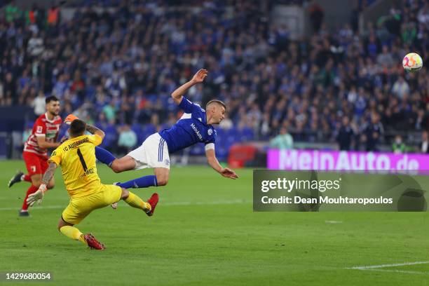 Simon Terodde of FC Schalke 04 is tackled by Rafał Gikiewicz of Augsburg during the Bundesliga match between FC Schalke 04 and FC Augsburg at...