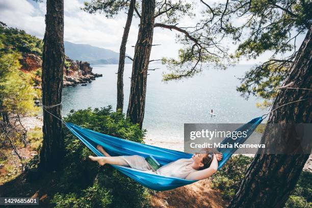 woman relaxing in hammock in the forest near the sea. - hamaca fotografías e imágenes de stock