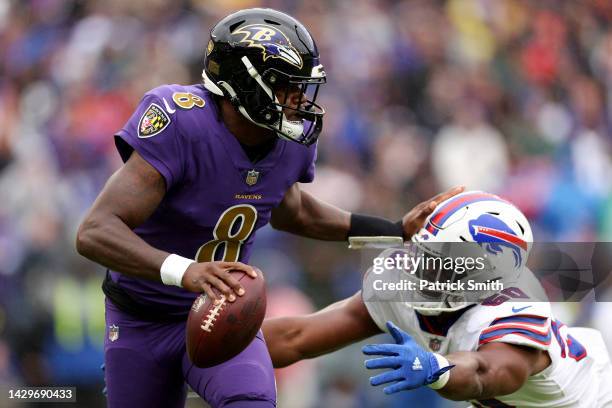 Lamar Jackson of the Baltimore Ravens drops back to pass while being chased by Greg Rousseau of the Buffalo Bills in the first quarter at M&T Bank...