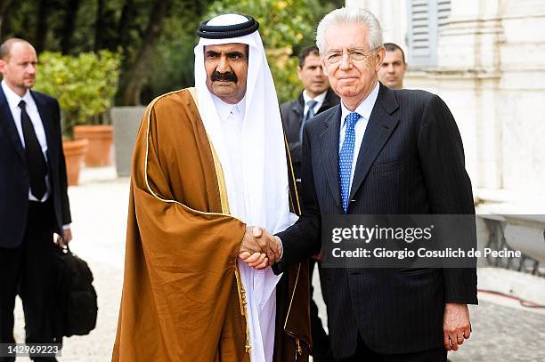 Italian Prime Minister Mario Monti and Qatari Emir Sheikh Hamad bin Khalifa al-Thani shake hands as they arrive for a bilateral summit at Villa...