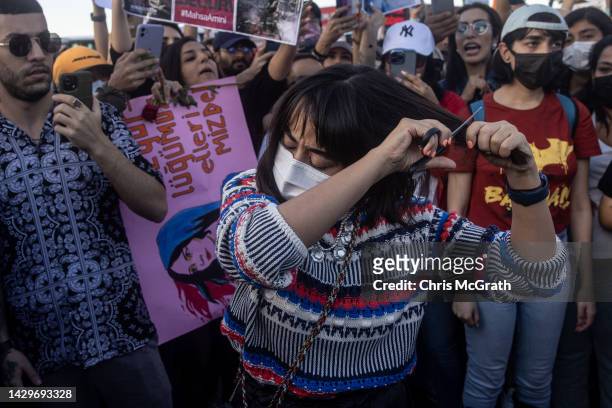 Woman cuts her hair during a protest against the death of Iranian Mahsa Amini and the government of Iran on October 02, 2022 in Istanbul, Turkey....