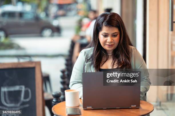 mid adult businesswoman working on laptop at a cafe - south asia stock pictures, royalty-free photos & images