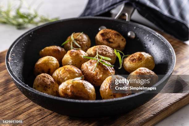 baked potatoes in a cast iron pan with rosemary. - baked potato stock pictures, royalty-free photos & images