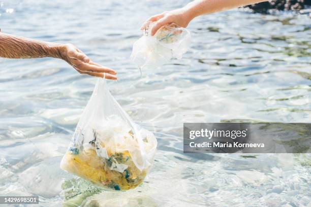 unrecognizable people cleaning beach from waste. - transparent bag stock pictures, royalty-free photos & images
