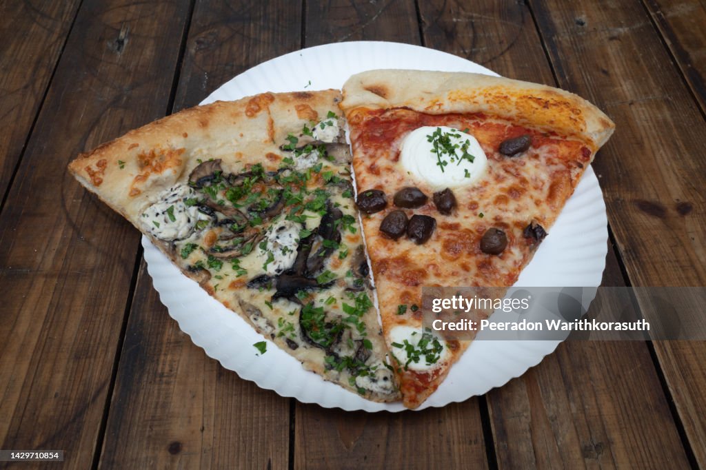 Sliced of truffle and ricotta pizza on paper plate and wooden table.