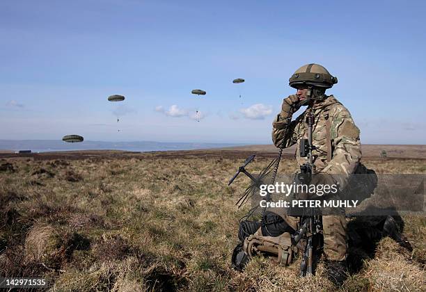 British soldier speaks on the radio as soldiers from the British 3rd Parachute Brigade jump from a Hercules C130 plane during the 16 Air Assault...