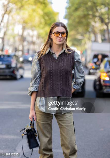 Camille Charriere wears brown v neck pull under, striped button shirt, green pants, black Hermes bag, brown heels outside Loewe during Paris Fashion...