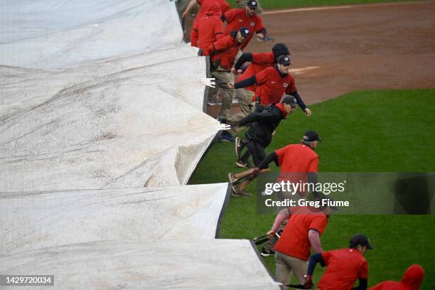 The grounds crew puts the tarp on the field after the end of the sixth inning of the game between the Philadelphia Phillies and the Washington...