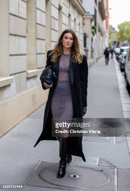 Camille Charriere wears see trough dress, black coat, bag, knee high boots outside during Paris Fashion Week - Womenswear Spring/Summer 2023 : Day...
