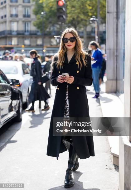 Olivia Palermo wears black double breasted coat, beige top, skirt with print, black over knees boots outside Giambattista Valli during Paris Fashion...