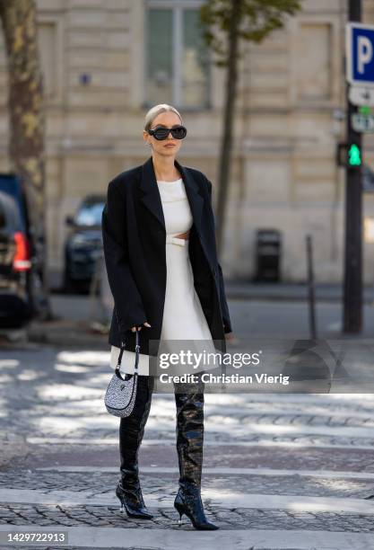 Leonie Hanne wears black cut out blazer, white dress, black over knees boots, silver outside Giambattista Valli during Paris Fashion Week -...