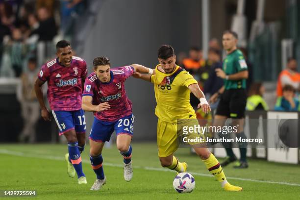 Alex Sandro of Juventus looks on as team mate Fabio Miretti battles for possession with Riccardo Orsolini of Bologna FC during the Serie A match...