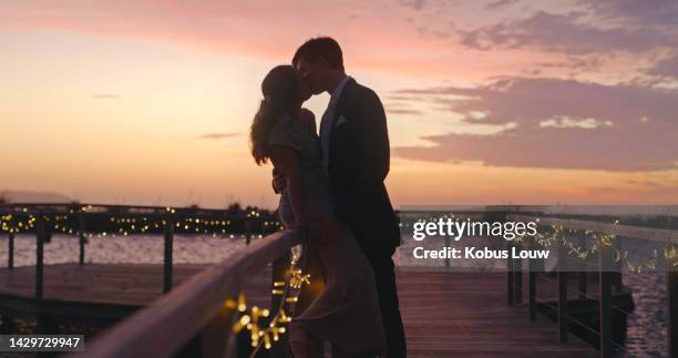 wedding, love and couple with a kissing bride and groom at sunset with a view on their marriage day. beautiful sky in the background of a man and woman sharing an intimate kiss after getting married - couple dark background stock pictures, royalty-free photos & images