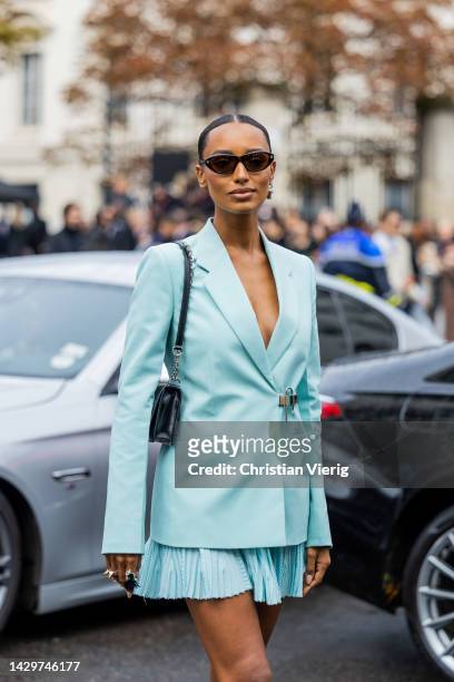 Guest wears turquoise blazer, pleated mini skirt, bag outside Givenchy during Paris Fashion Week - Womenswear Spring/Summer 2023 : Day Seven on...