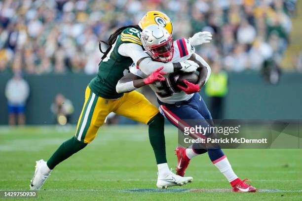 De'Vondre Campbell of the Green Bay Packers tackles Rhamondre Stevenson of the New England Patriots during the second quarter at Lambeau Field on...