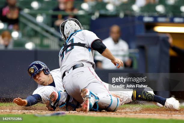 Luis Urias of the Milwaukee Brewers is tagged out at home plate by catcher Jacob Stallings of the Miami Marlins in the tenth inning at American...