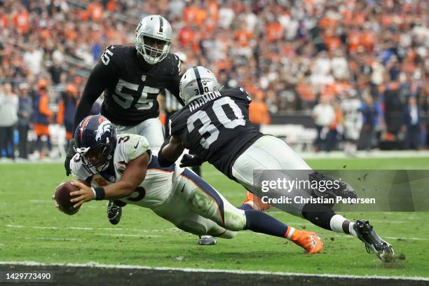 Russell Wilson of the Denver Broncos dives for a touchdown past Duron Harmon of the Las Vegas Raiders in the fourth quarter at Allegiant Stadium on...