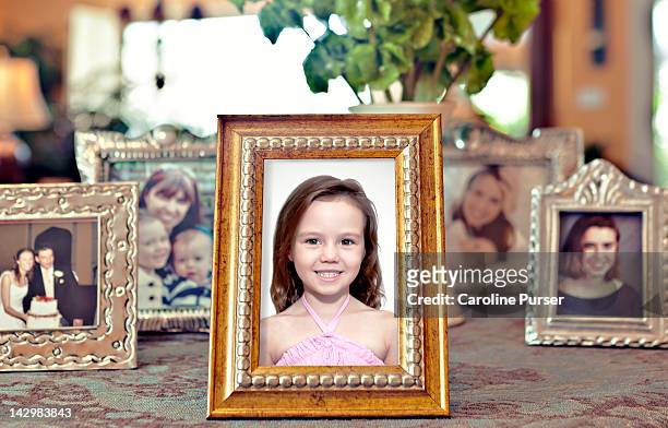 young girl's picture in a frame with others behind - tischflächen aufnahme stock-fotos und bilder