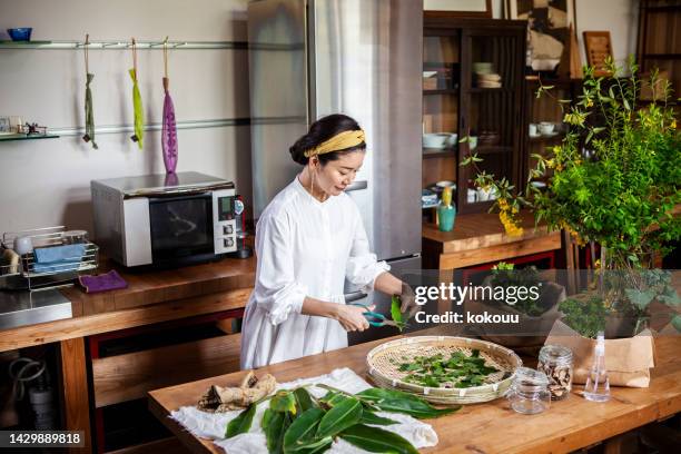 a woman cutting herbs and vegetables in the kitchen. - chef market stock pictures, royalty-free photos & images