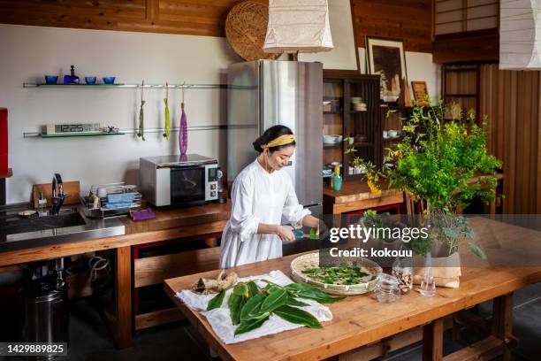 a woman cutting herbs and vegetables in the kitchen. - chopped herbs stock pictures, royalty-free photos & images