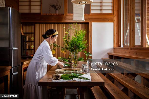 a woman cutting herbs and vegetables in the kitchen. - herbal medicine imagens e fotografias de stock