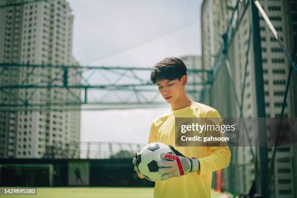 goalkeeper holding soccer ball against goal post. - young men playing soccer stock pictures, royalty-free photos & images