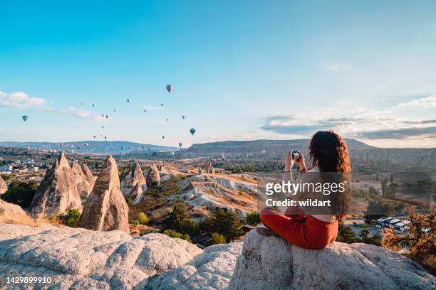 traveler photographer girl takes photo of hot air balloons during sunrise in cappadocia nevsehir , turkey - cappadocia hot air balloon stock pictures, royalty-free photos & images