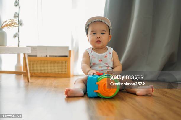 a cute 9 month asian baby sitting on floor, playing with toys - busy toddlers stock pictures, royalty-free photos & images