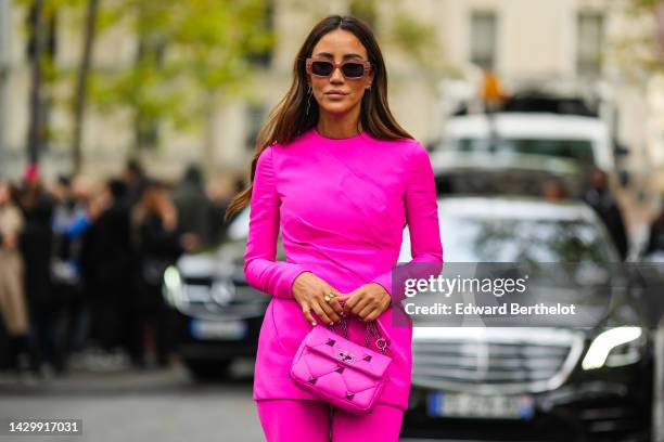 Tamara Kalinic wears pink square sunglasses, a neon pink long sleeves / short tube dress from Valentino, neon pink tights, gold rings, a neon pink...