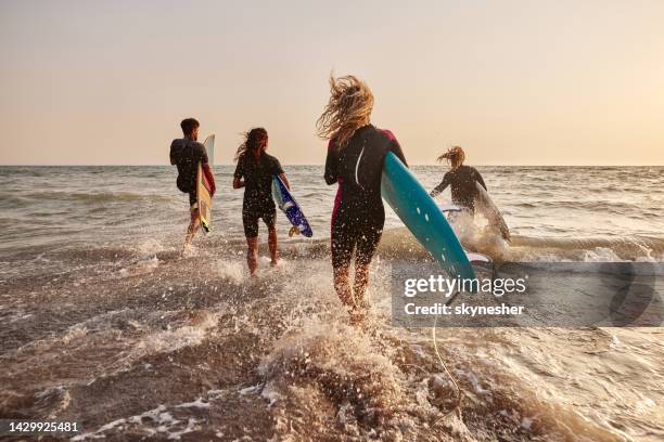 rushing to surfing! - surfers in the sea at sunset bildbanksfoton och bilder