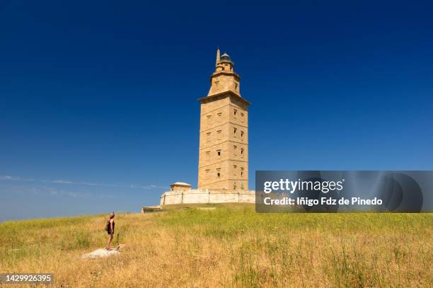woman looking at the tower of hercules, a coruña, galicia, spain. - 拉科魯尼亞 個照片及圖片檔
