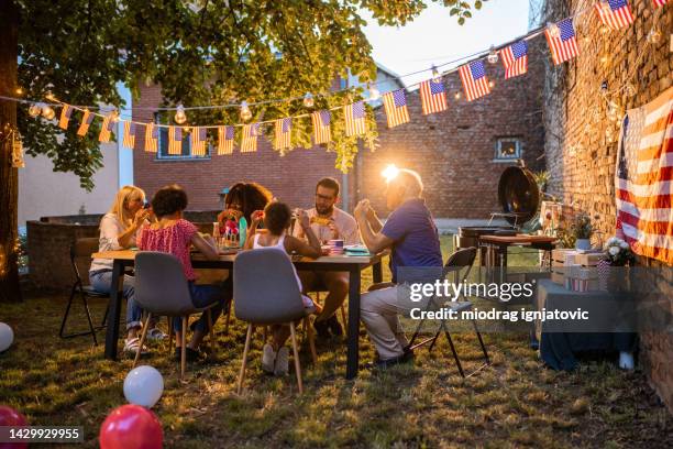 familia de varias generaciones cenando al aire libre en una fiesta nacional estadounidense - 4th of july cookout fotografías e imágenes de stock