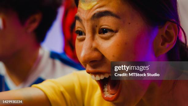 close-up grupo de adolescentes asiáticos felizes sentam-se no sofá assistir cheer jogos de futebol online juntos à noite. - cu fan - fotografias e filmes do acervo