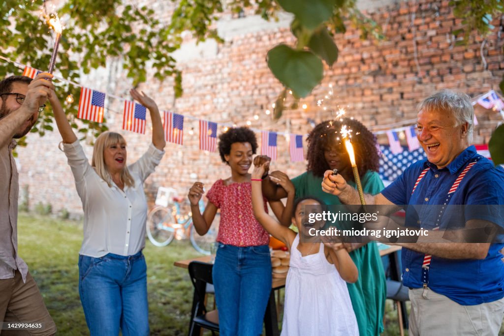 Multi-generation family waving sparklers outdoors on an American national holiday