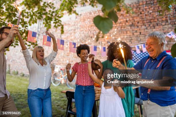 multi-generation family waving sparklers outdoors on an american national holiday - onafhankelijkheidsdag stockfoto's en -beelden