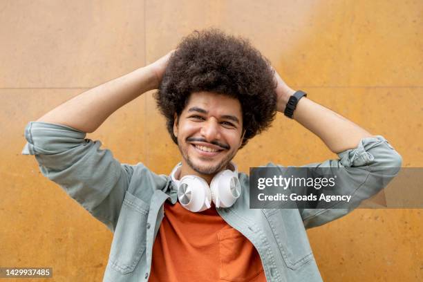 man with headphones around his neck touching his afro hair - headphone man on neck stock pictures, royalty-free photos & images