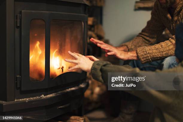 father and son warming hands by a fireplace - fire place stock pictures, royalty-free photos & images