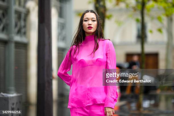 Guest wears a neon pink turtleneck / silk blouse from Valentino, neon pink suit pants from Valentino, a neon pink shiny leather handbag from...