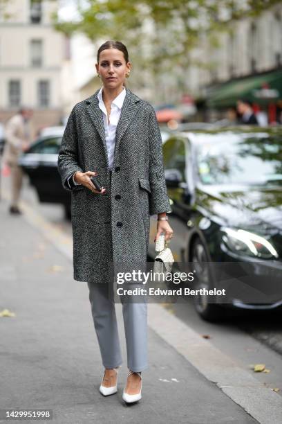 Guest wears gold earrings, a white shirt, gold chain necklaces, a black and white striped print pattern wool buttoned coat, pale gray shiny leather...